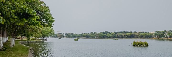 Serene view of a tranquil park lake with lush green trees, ideal for nature relaxation and environmental awareness