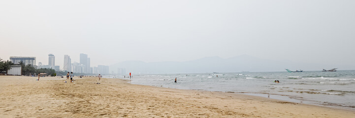 Fototapeta premium A nearly empty Asian beach with a hazy sky, highlighting environmental pollution on a summer day