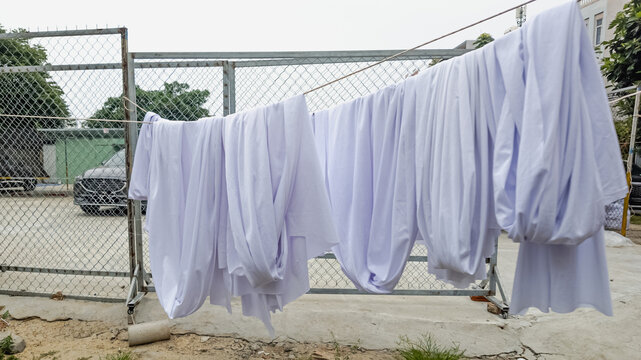 White sheets drying on a clothesline outdoors, symbolizing cleanliness and sustainability in a residential neighborhood