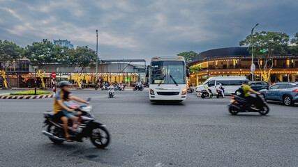 Busy urban intersection with motorbikes and a bus in Vietnam, illustrating traffic congestion and daily life routine