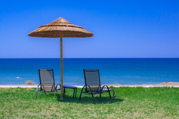 Sonnenschirm und zwei Liegestühle am Strand im Hotel Strandabschnitt vor dem Meer Ozean