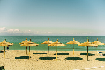 Straw umbrellas nailed to the edge of the beach.