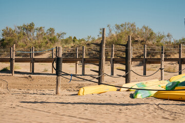 Wooden walkway on the beach with canoes in the sand.