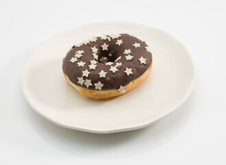 Donuts de chocolate con estrellas  de azúcar sobre plato. Chocolate donuts with sugar stars on a plate.