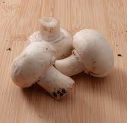 Champiñones frescos sobre tabla de madera, vista cenital. Fresh mushrooms on wooden board, overhead view.
