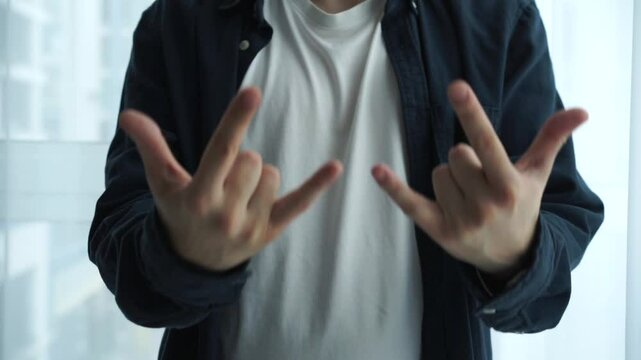 A faceless man in a white T-shirt and shirt demonstrates the symbol of rock and roll music.