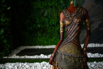 a female statue with a plant in her hair stands in a garden