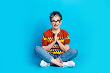 Full size photo of nice aged woman sit floor plead wear t-shirt isolated on blue color background