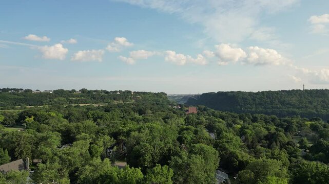 Aerial lifting up overlooking the Niagara River Escarpment from Lewiston in western New York, United States with the Queenston Lewiston international border crossing and Canada in the distance. 2024.