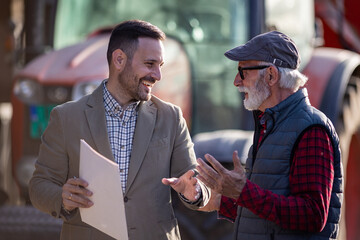 Bank agent talking to farmer on farm about contract © Budimir Jevtic
