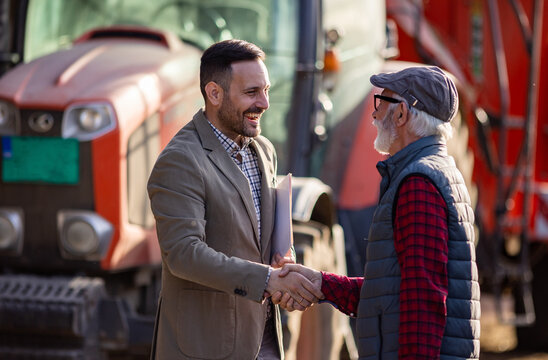 Bank agent and farmer shaking hands on farm