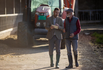 Business man and farmer looking at tablet on ranch