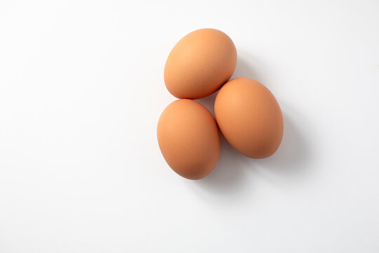 Top View of Three Brown Eggs on a White Background with Copy Space