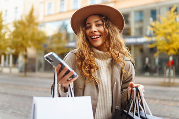 Fall elegant woman carrying shopping bags walking city street. Consumerism, sale, purchases,...