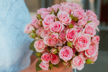 Bright Beautiful bridal bouquet with roses and ribbon in bride's hand