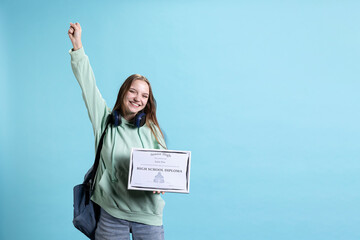 Portrait of smiling student holding high school diploma, feeling overjoyed and celebrating...