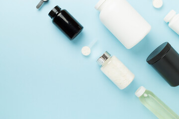 Jars with protein powder on color background, top view. Sports nutrition concept