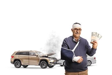 Mature man with a broken arm and bandage on head holding money in front of car crash