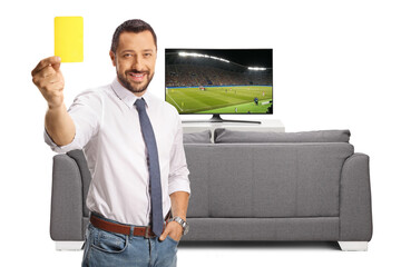 Businessman showing a yellow card in front of tv screen and smiling