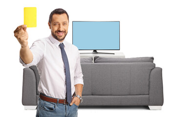 Businessman showing a yellow card in front of tv and smiling