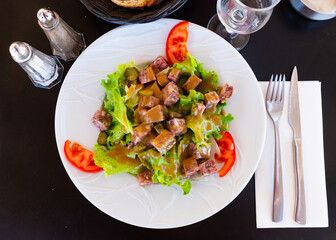 Traditional French cuisine, salad with chopped headcheese, fresh lettuce leaves, pickled cucumbers and tomatoes