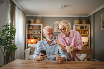 Fototapeta premium Senior couple buy online whit credit card on mobile phone at home