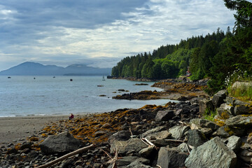 A small beach at Herring Cove near Ketchikan, Alaska, is framed by forests, the sea, and distant mountains