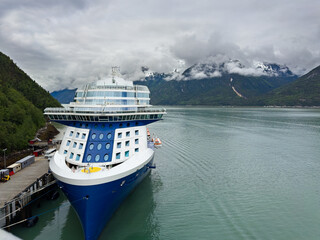 A cruise ship docked at Skagway, Alaska, with cloud-covered mountains in the background
