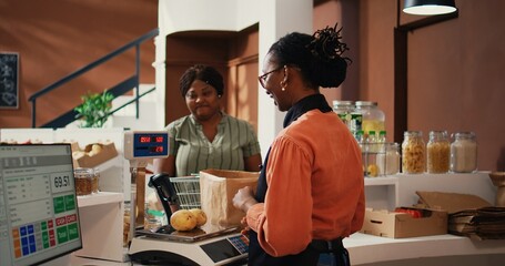 Local vendor scanning and weighting products for client, buying bulk products and vegetables. African american buyer and merchant talking about vegan nutrition and healthy lifestyle. Handheld shot.