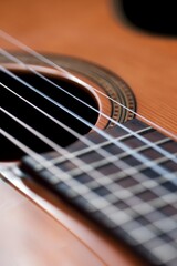 Fototapeta premium Extreme view of a guitar with a shiny coating. Strings of a guitar with intricate patterns of shiny wood.