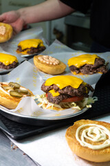 cheeseburgers in the making, chef preparing smash burgers in the kithcen of a burger shop