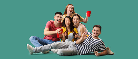 Group of young friends with beer and ball on green background