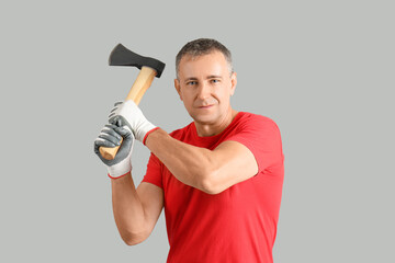 Portrait of adult lumberjack swinging axe on grey background