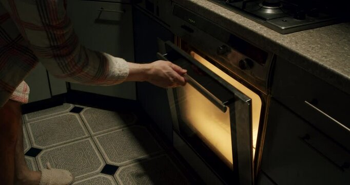 Man burnt the dinner dish in the oven. Man opening an oven full of smoke in the kitchen. Dinner ruined, left burnt and spoiled. Kitchen incident. Man lack of attention and ineptitude