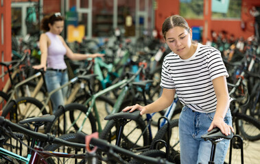 Obraz premium Enthusiastic young female customer choosing new bike with comfortable saddle ensuring pleasant cycling experience in store