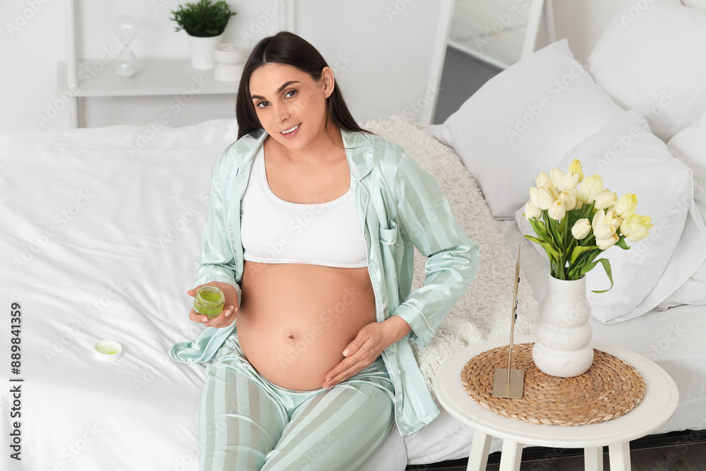 Canvas Prints Young pregnant woman with jar of cream sitting in bedroom