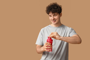 Sporty guy opening bottle of water on beige background