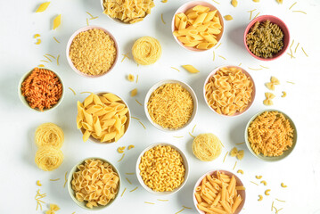 Bowls with different raw tasty pasta on white background
