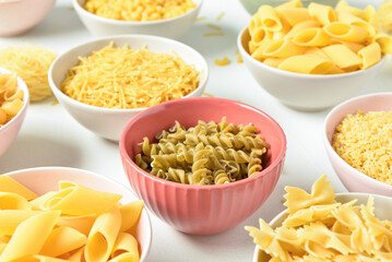 Bowls with different raw tasty pasta on white background, closeup