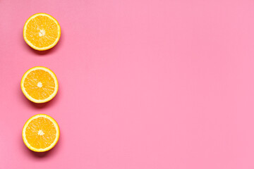 Composition with ripe tasty halves of oranges on pink background