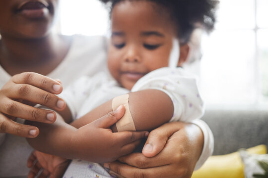 Mother, daughter and care with plaster for injury, bruise or sore arm in trust, love or support at home. Mom applying bandaid on young girl, kid or child on pain relief or medical healthcare at house
