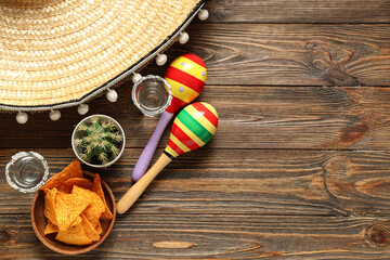 Mexican maracas with sombrero, tequila and nachos on wooden background. Cinco de Mayo