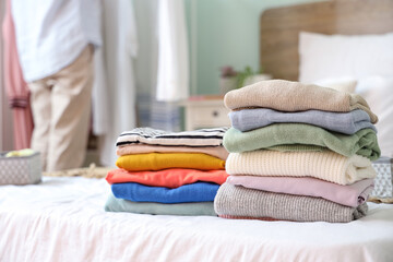 Stacks of different clothes on bed in room, closeup