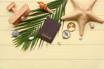 Composition with passport, vintage compass, palm leaf and starfish on color wooden background