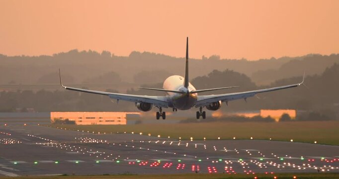 Airplane landing at sunset. Big passenger plane landing on the runway. Passenger plane landing towards the runway. 