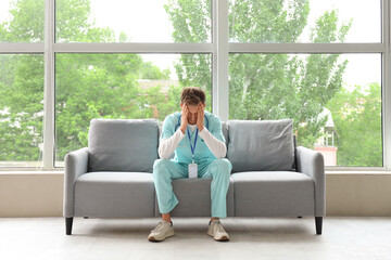 Stressed medical intern sitting on sofa in clinic