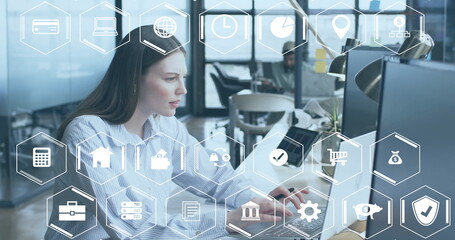 Image of business and finance icons over caucasian businesswoman using computer at office desk