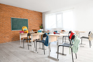 Interior of classroom with chalkboard, desks and backpacks