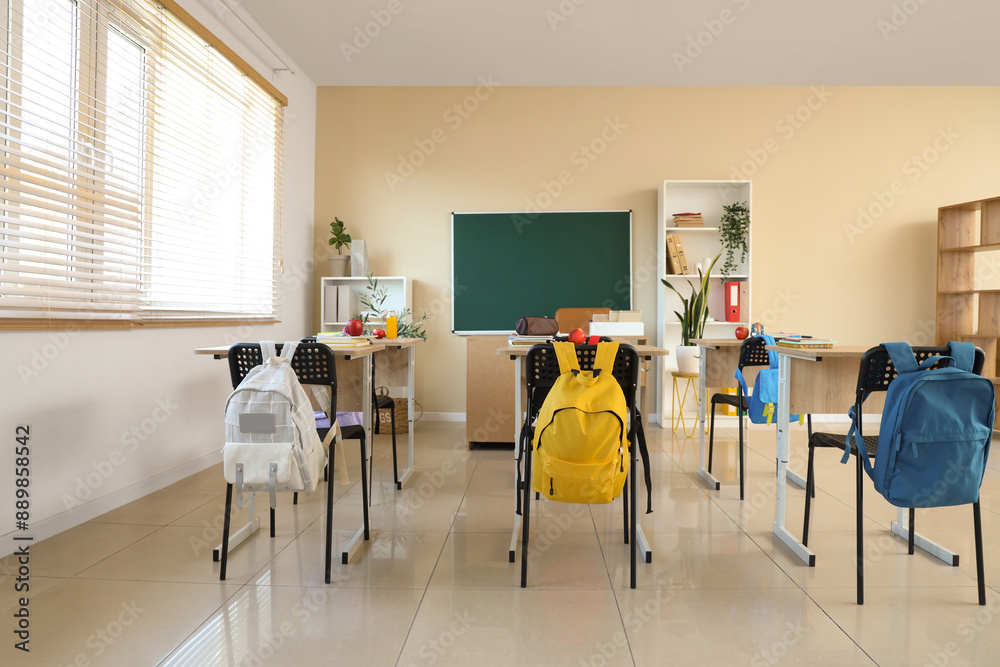 Wall mural interior of empty classroom with desks and backpacks on chairs