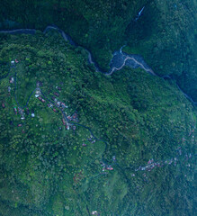 Aerial view Kabut Pelangi Waterfall in East Java. The waterfall crashes down into the amphitheater below, which is covered in lush green plants. Above is the residence of the villagers.